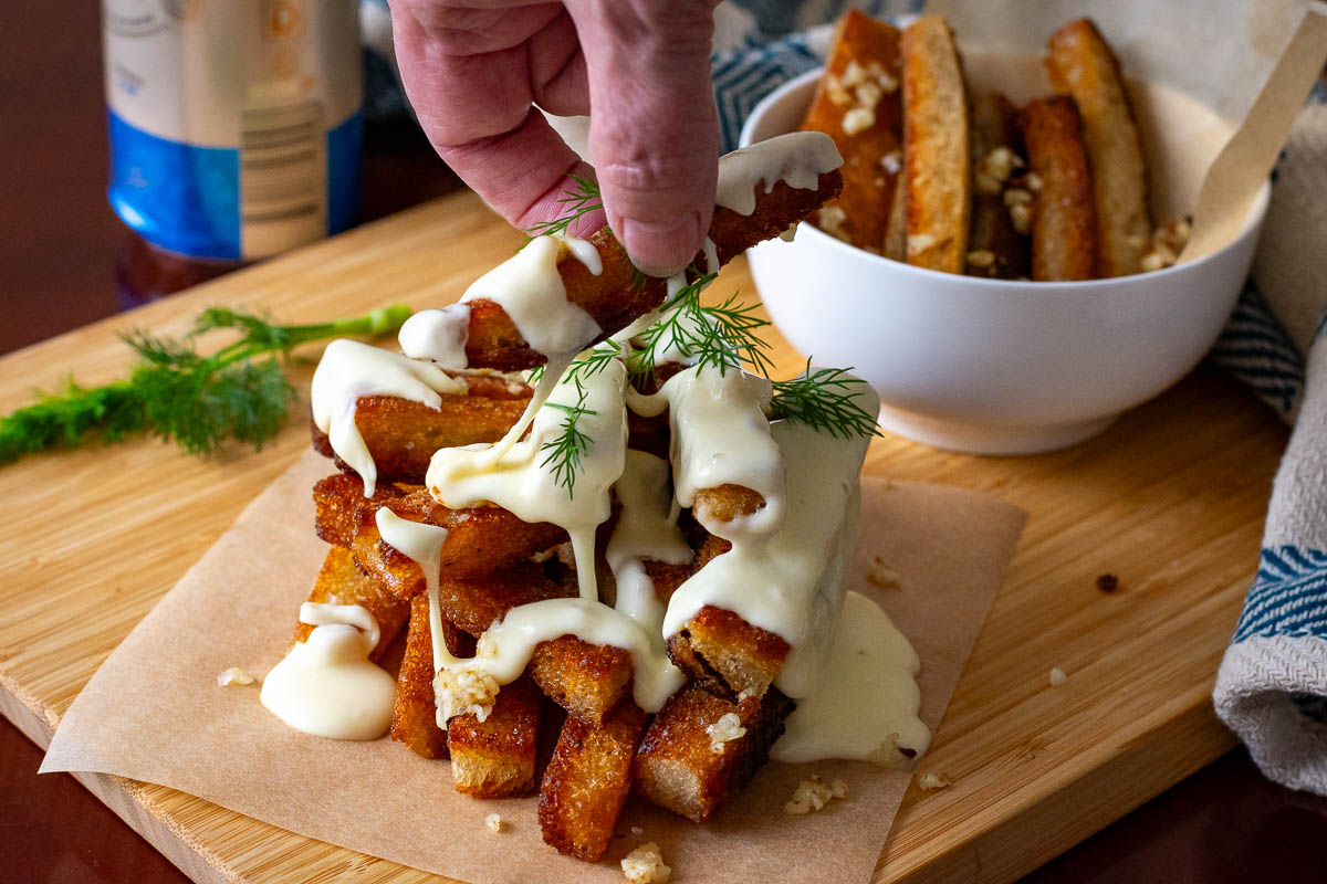 A piece of LIthuanian fried bread, known as Kepta Duona, being picked up createing a cheese pull. 