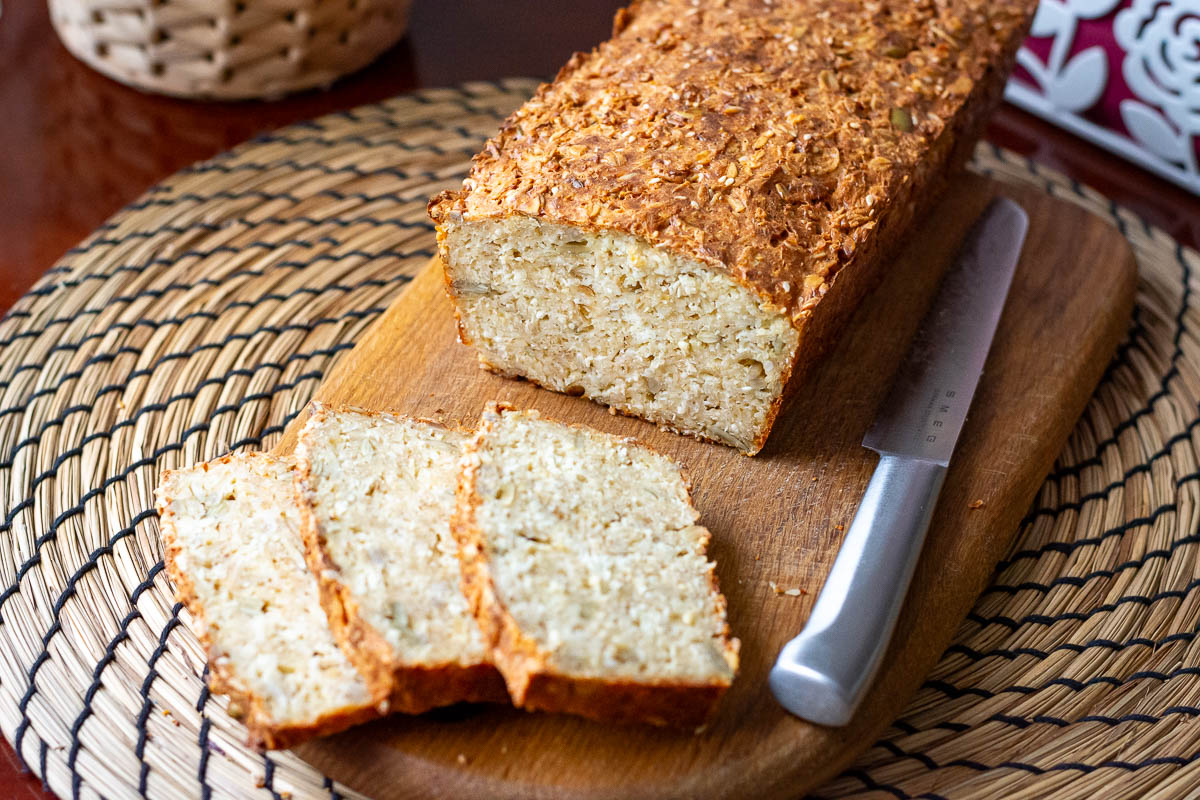 Lithuanian Farmer's Cheese bread with seeds and oats with three slices cut on a wooden board.