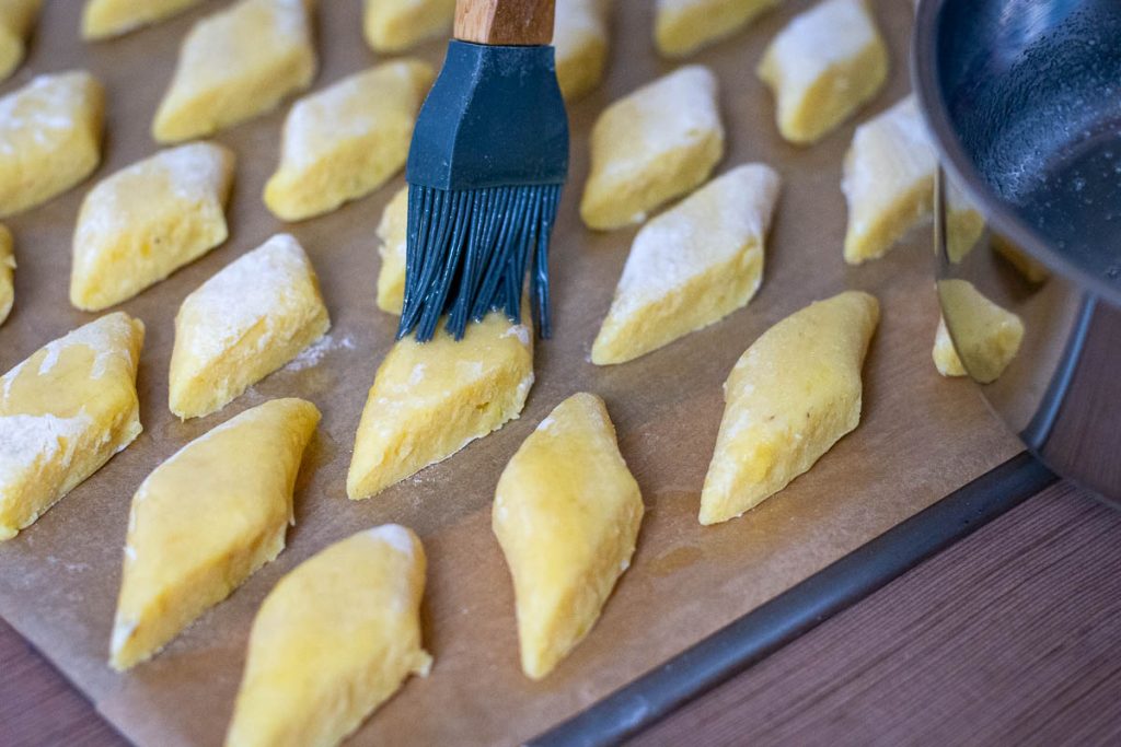 Brushing each potato bite with butter.