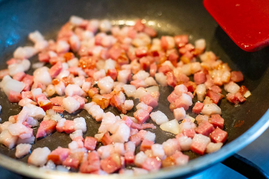 Pancetta crisping up in a frying pan.