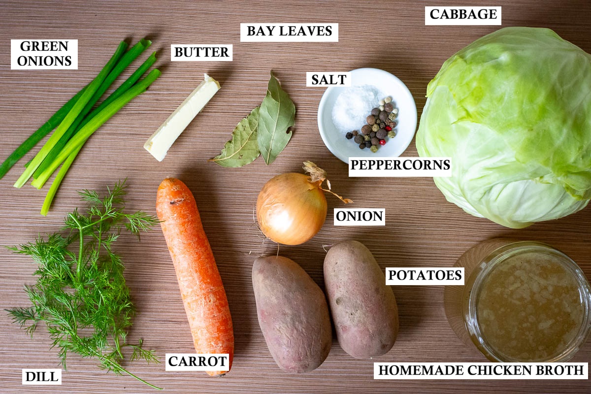Labelled ingredients for Lithuanian cabbage soup on a wooden worktop surface.