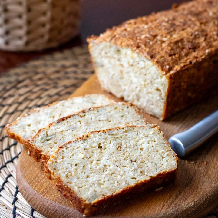 Lithuanian Farmer's Cheese bread with seeds and oats with three slices cut on a wooden board.