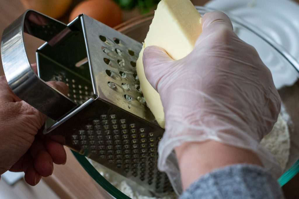 Grating frozen butter into the flour.