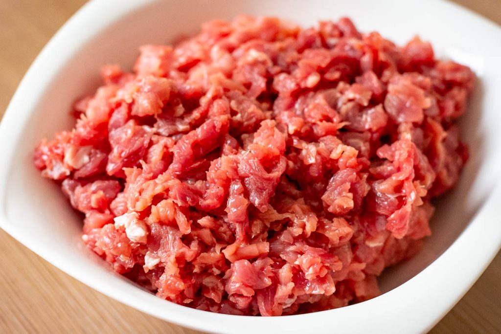 Finely diced pork in a white bowl.