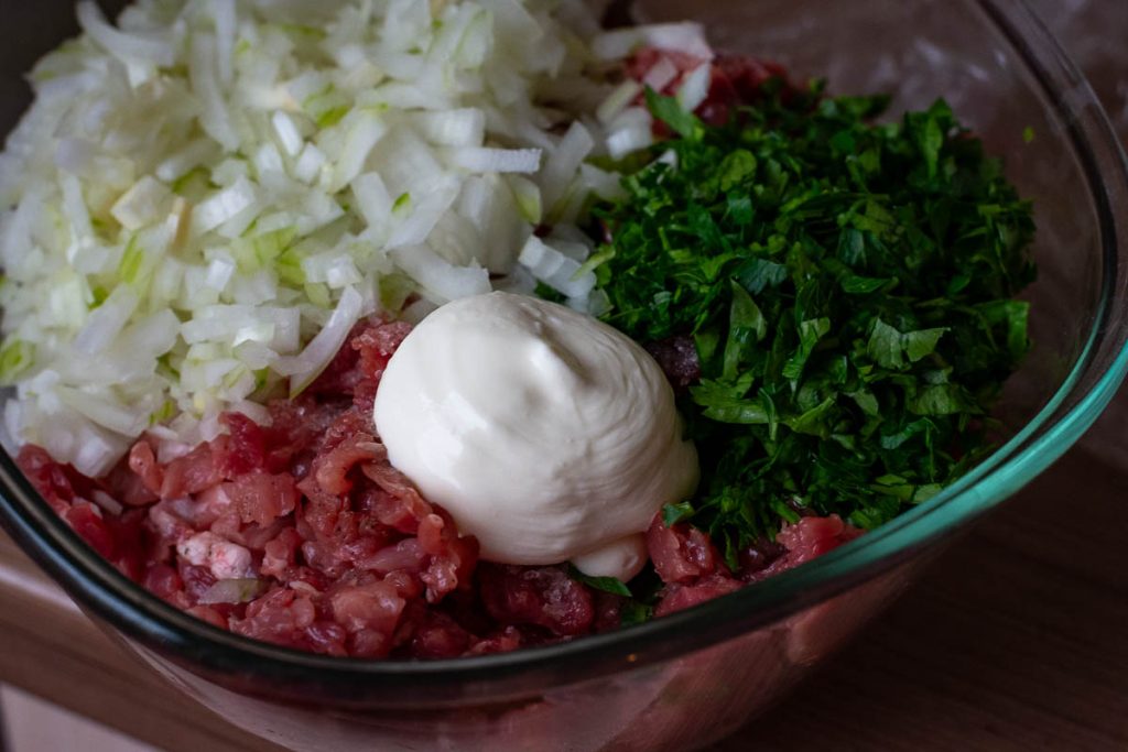 Pork, onions, parsley and sour cream in a bowl.