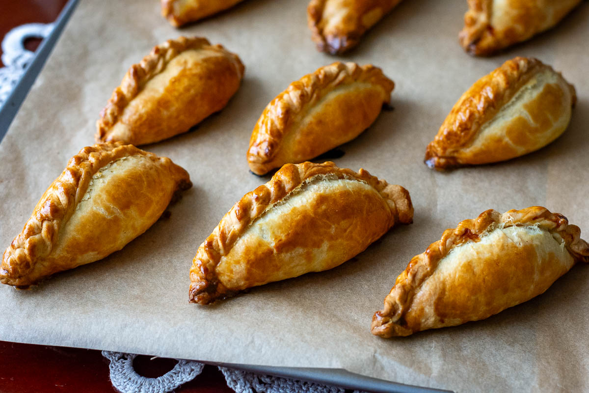 Golden brown Lithuanian Meat Pies on a baking sheet lined with parchment paper.