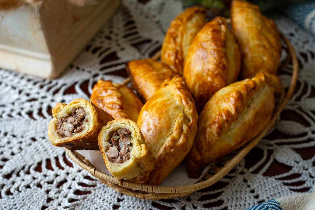 A bunch of Lithuanian meat pastries arranged in a whicker platter.