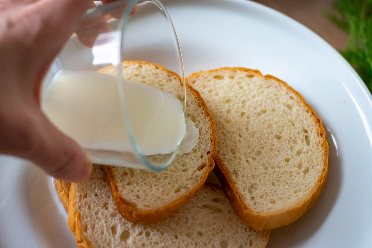 Pouring milk over white bread to soak.