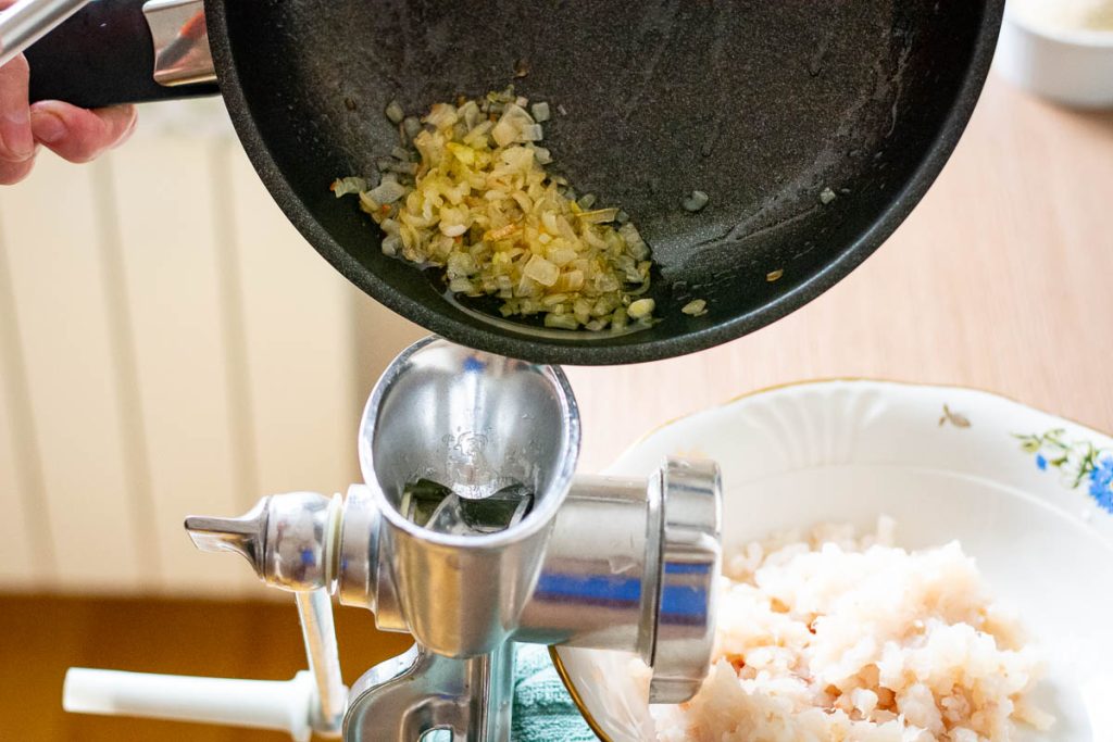 Adding onion to the meat mincer.