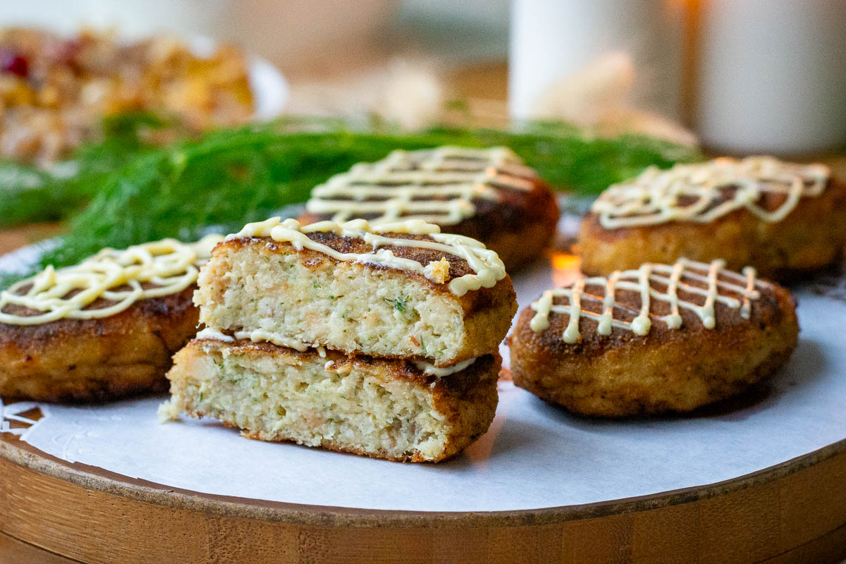 Pollock fishcakes on a wooden board with one cut in half.
