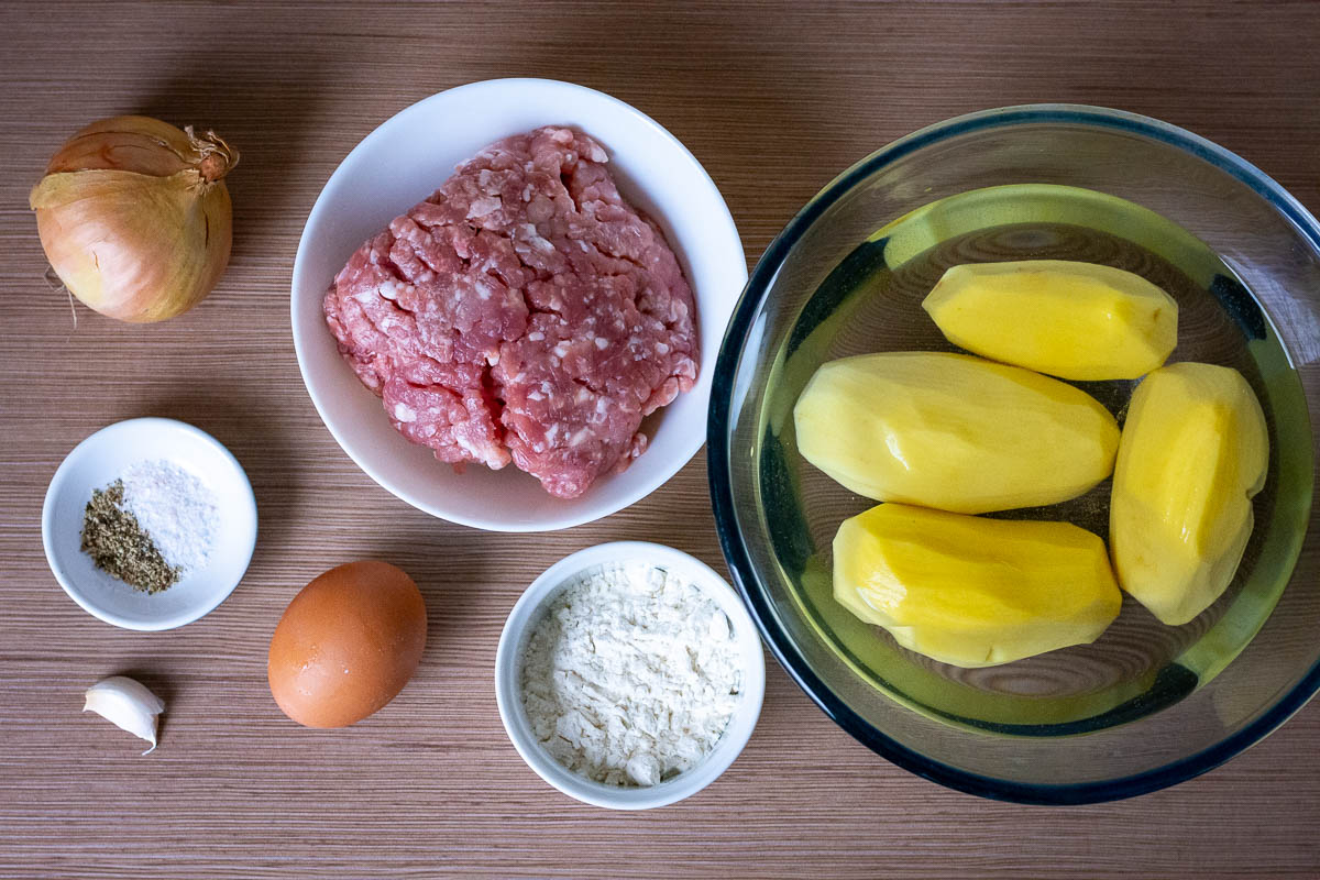 Ingredients for Lithuanian ground meat stuffed potato pancakes on a wooden table.
