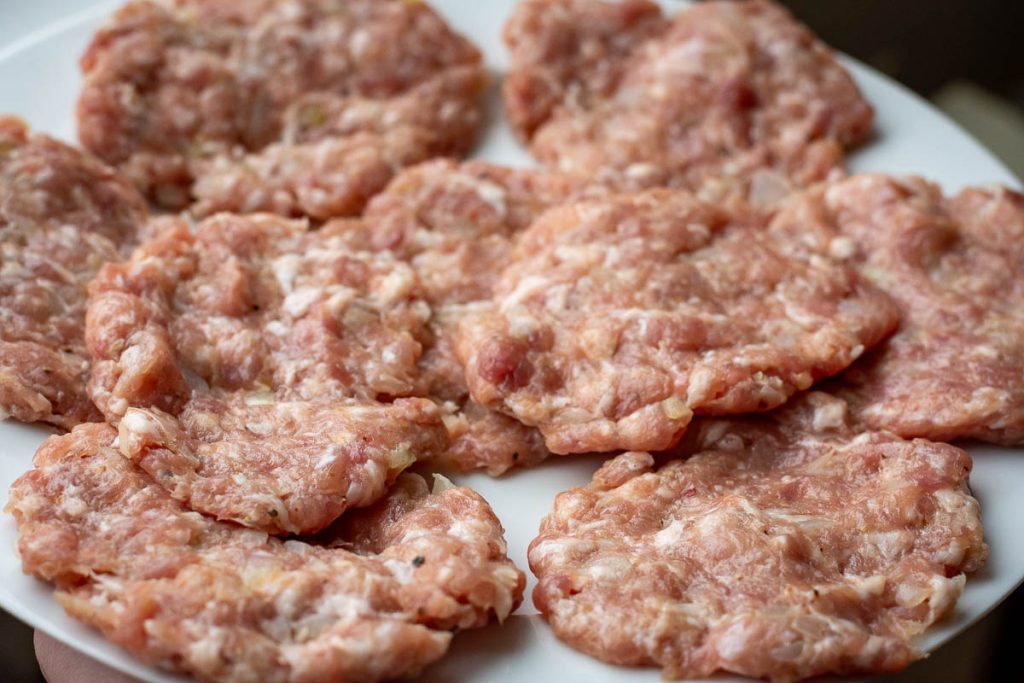 Sahped pork patties on a white plate.