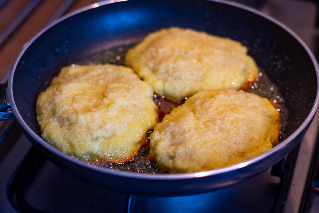 Lithuanain meat stuffed potato pancakes frying in a pan.