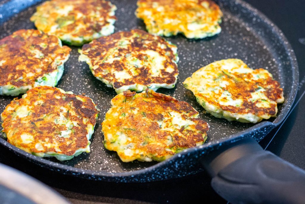 Golden brown Lithuanain zucchini pancakes in a frying pan.