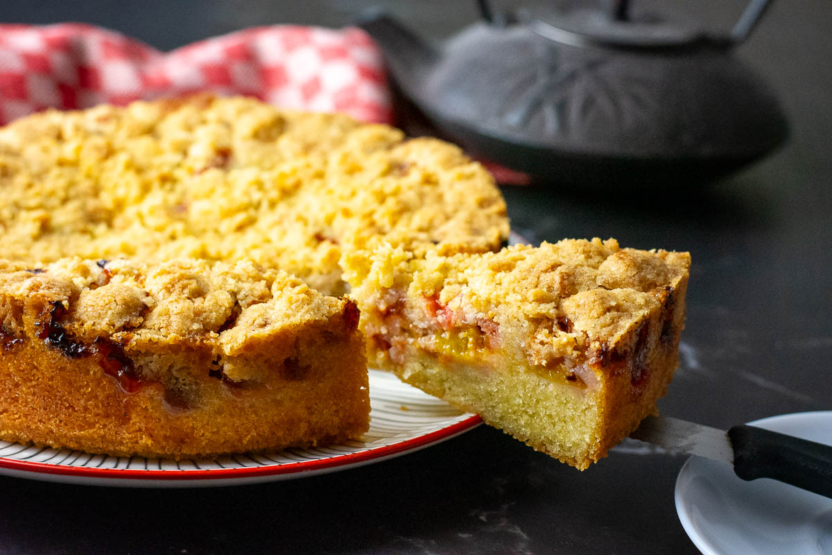 A slice of Lithuanian plum cake being cut.