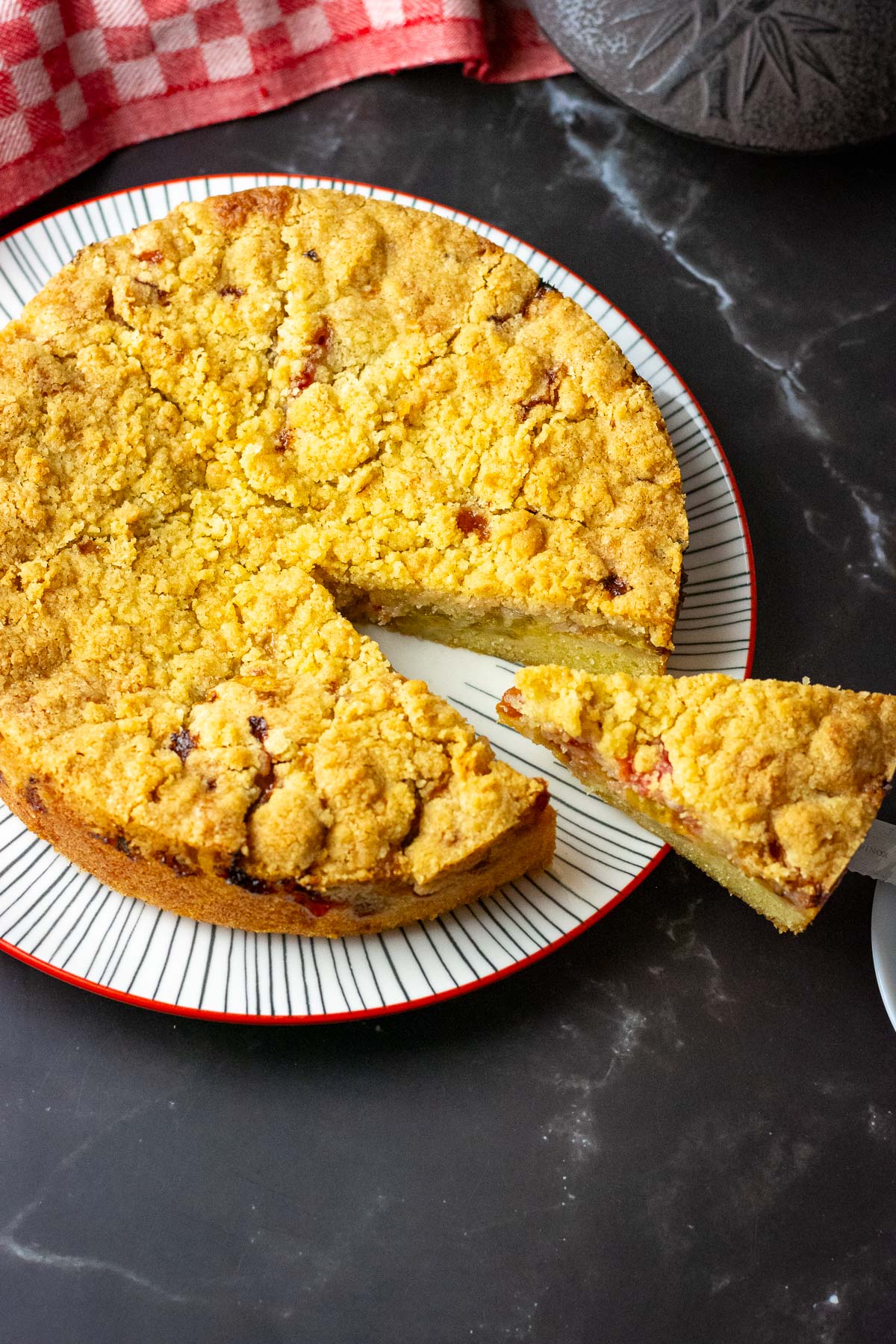 Lithuanian plum crumb cake with one slice being cut.