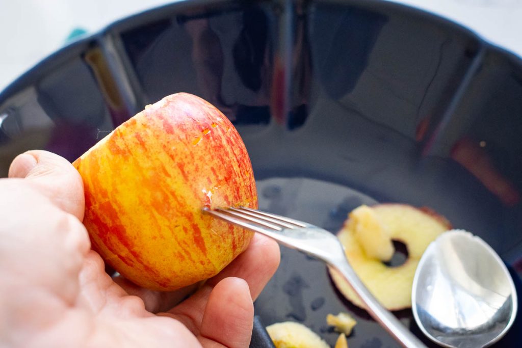 Pricking the hollowed apples with a fork to prevent the skin from bursting.