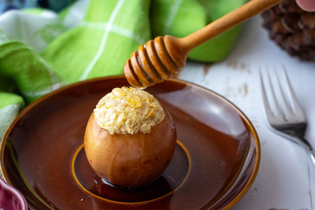Drizzling honey over the top of the Lithuanian baked apple filled with farner's cheese.