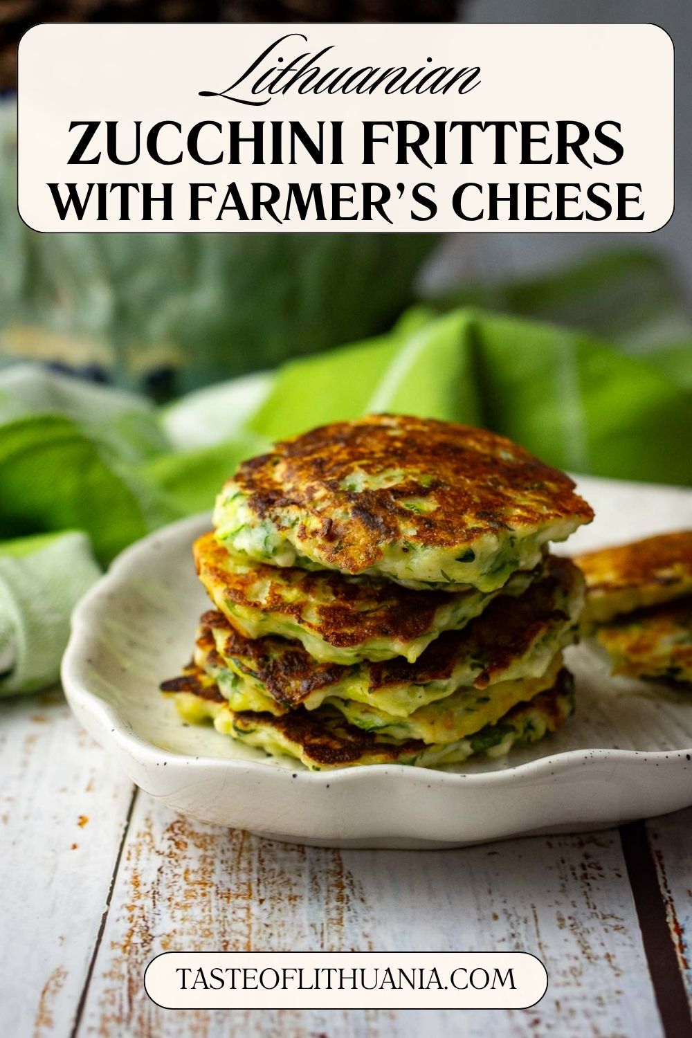 A stack of soft Lithuanian Zucchini fritters with farmer's cheese on a white plate. Pin for Pinterest.