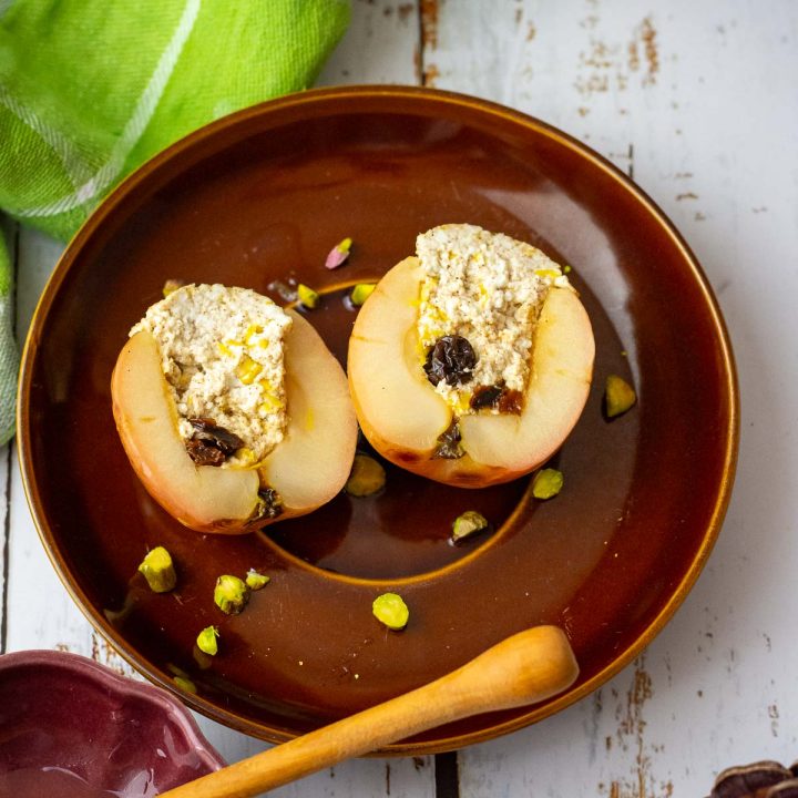 Lithuanian baked apple with farmer's cheese filing cut open on a brown plate.
