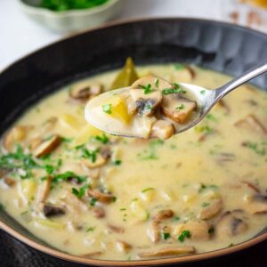 A spoonful of Lithuanian mushroom soup being taken out of a bowlful of it.