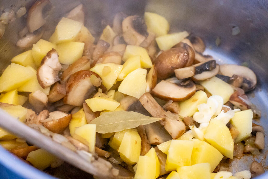 Potatoes and bay leaf added to sauteed mushrooms. 
