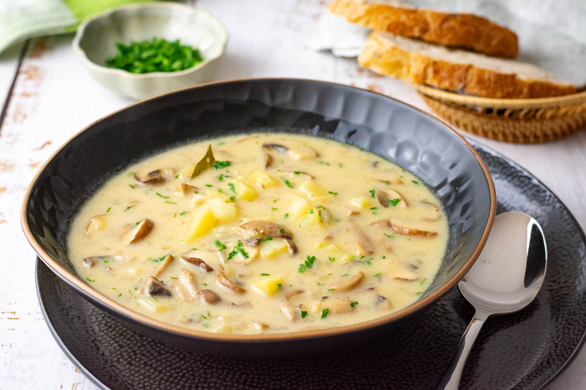 Lithuanian mushroom soup served in a black bowl with a little parsley on top. 
