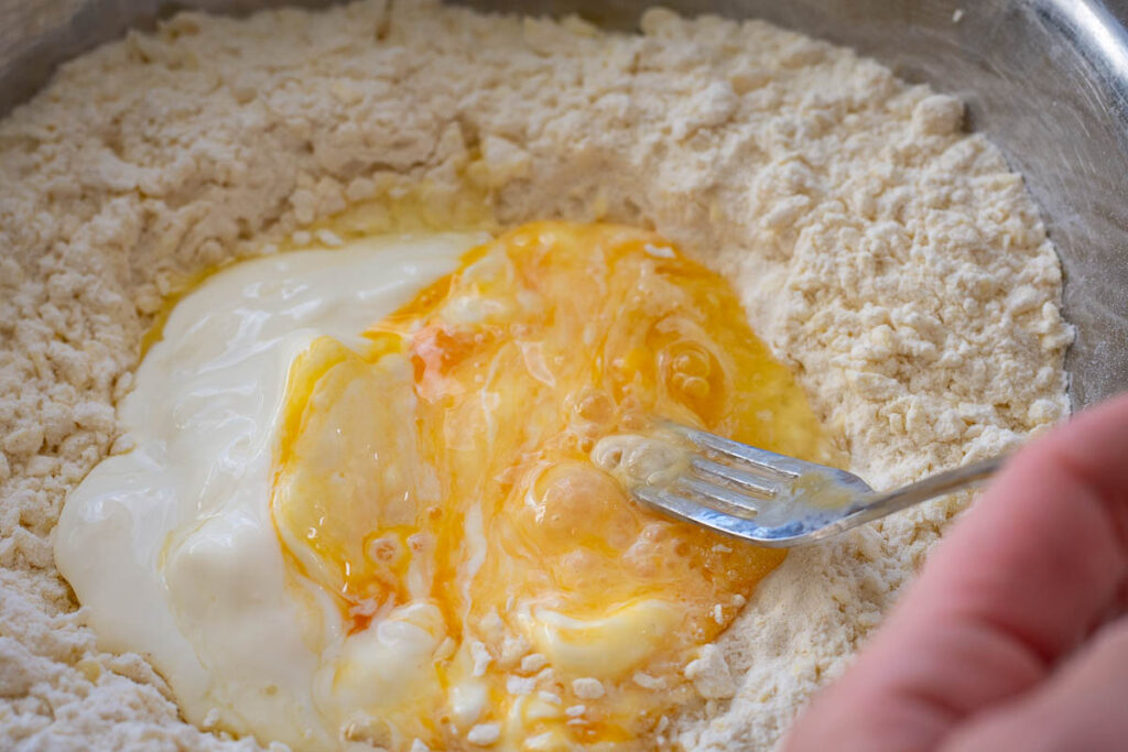 Whisking the egg and sour cream in the well of the flour.