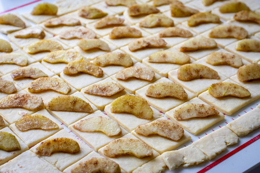 A piece of apple placed diagonally on each piece of pastry.