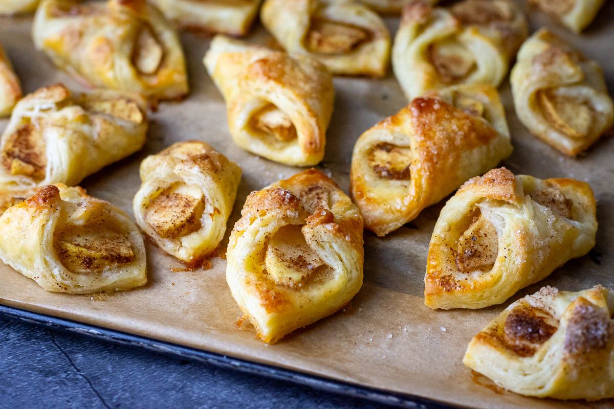 Lithuanian apple cookies, also known as Skarelės su obuoliais, on a baking sheet lined with parchment paper.