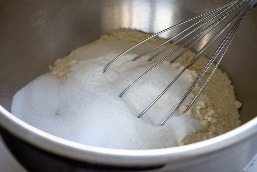Stirring dry ingredeints together in a large bowl with a balloon whisk.