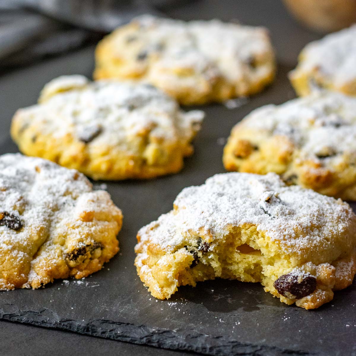 Lithuanian Rock Cakes, known as Roksai, on a black serving board, dusted with powdered sugar.